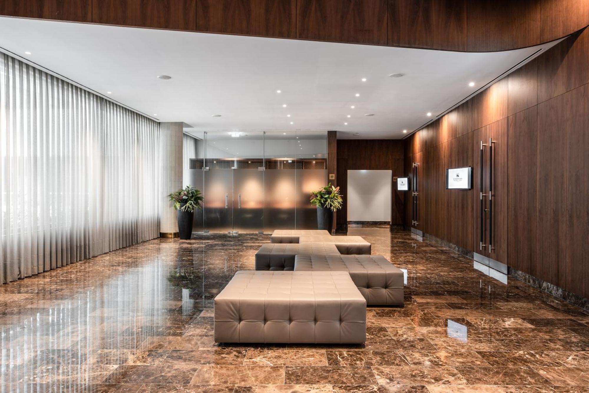 Eurostars Universal Lisboa 外观 照片 The photo shows a modern and elegantly designed lobby space. The walls are finished in dark wood, complementing the polished marble floor, which has a glossy appearance. There are large, floor-to-ceiling windows covered with sheer curtains that allow