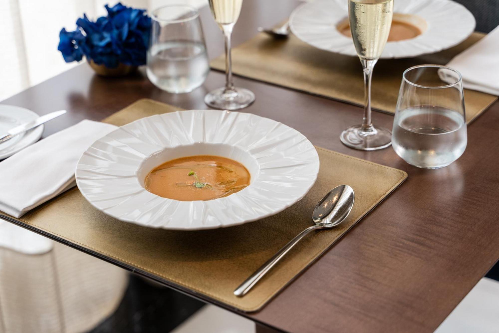 Eurostars Universal Lisboa 外观 照片 The photo displays an elegant dining setting. In the center, there's a large white plate with a decorative edge, containing a serving of soup, garnished with a few sprigs of herbs. Surrounding the plate, there are two glasses of sparkling wine, and a
